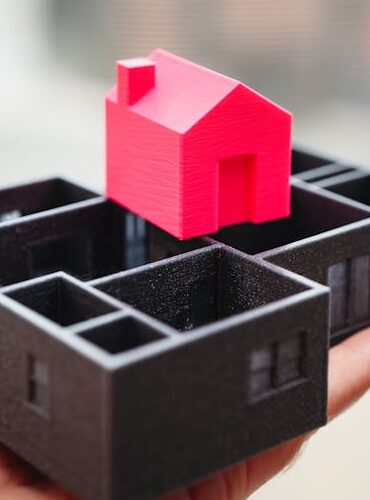 A hand holding a 3D printed model of a house and floor plan, showcasing architectural design.