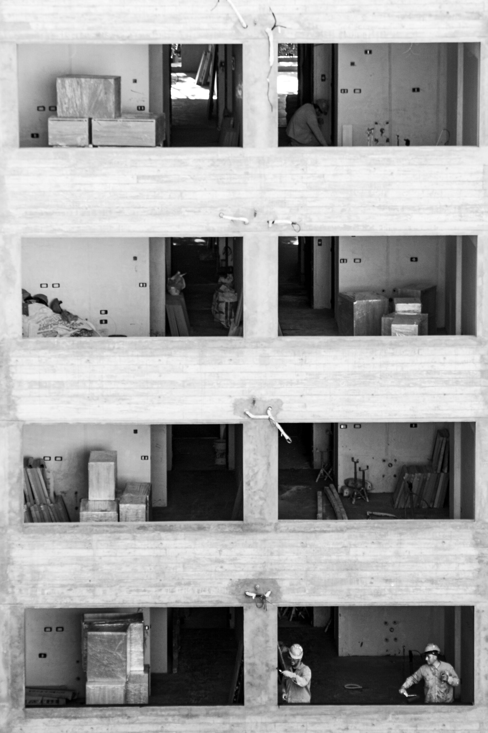 Workers at a multi-story building site in Buenos Aires, captured in monochrome.